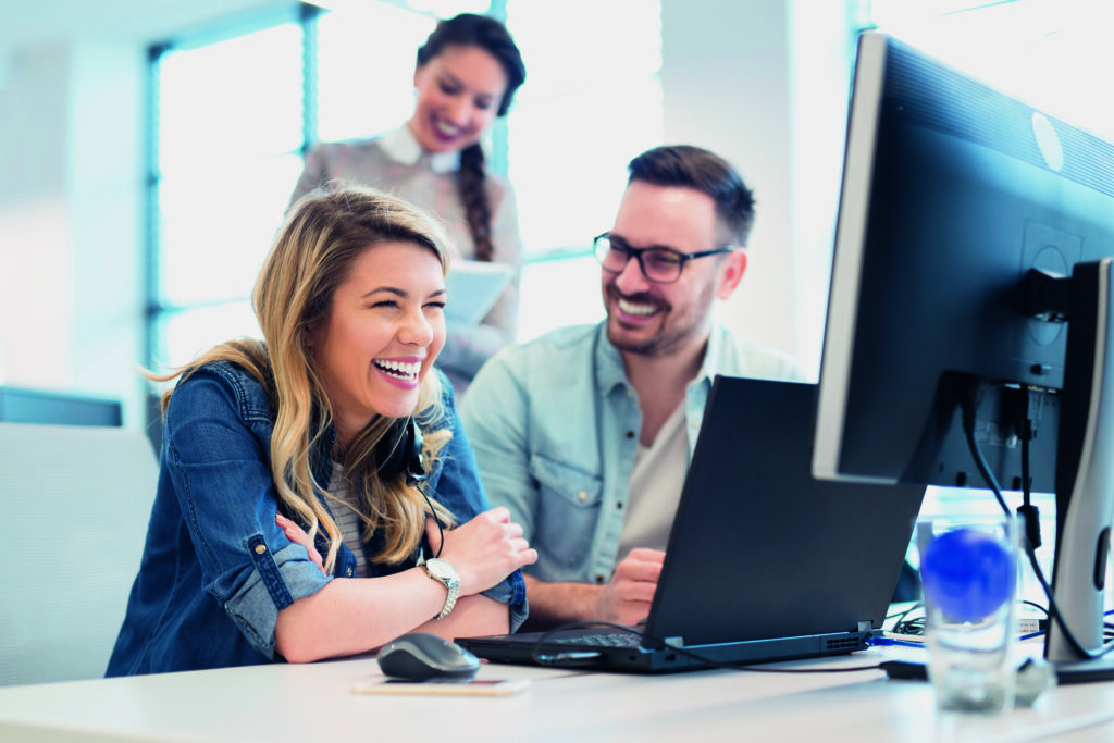 Menschen arbeiten am PC und unterhalten sich.